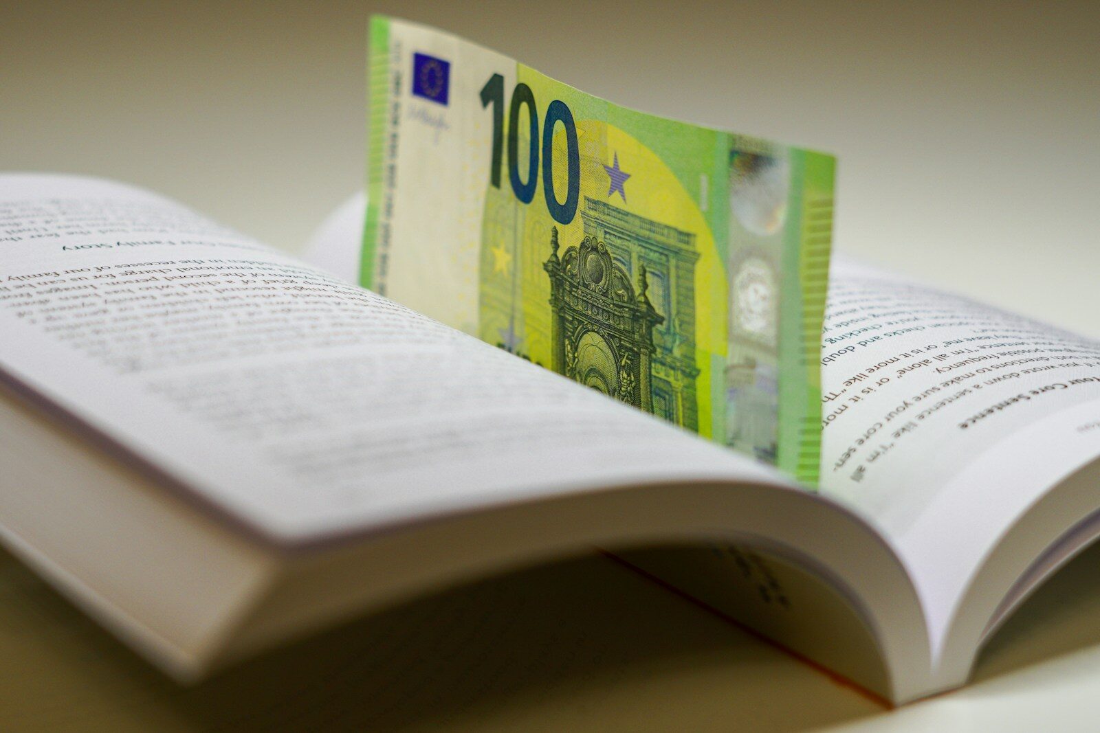 a hundred euros bill sticking out of an open book